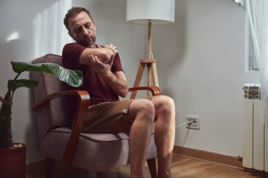 Dirseği, kolu ve bileği ağrıyan yetişkin bir adam..