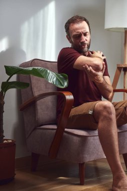 Dirseği, kolu ve bileği ağrıyan yetişkin bir adam..