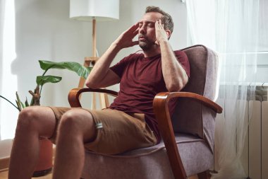 Başı ağrıyan bir adam evde oturuyor..