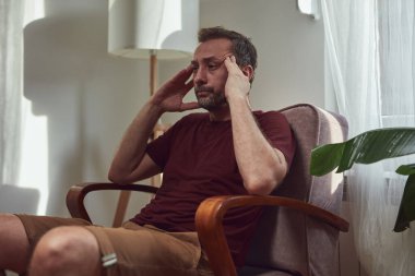 Başı ağrıyan bir adam evde oturuyor..