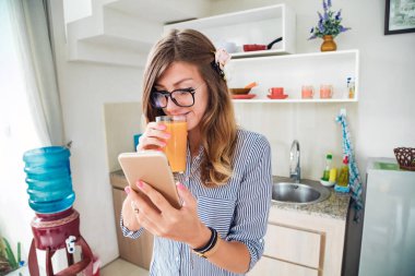 Modern bir evde akıllı telefon kullanan genç bir kadın..