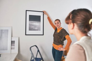 Anne ve kızı evde resim ve fotoğraf asıyorlar..