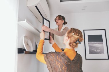 Anne ve kızı evde resim ve fotoğraf asıyorlar..