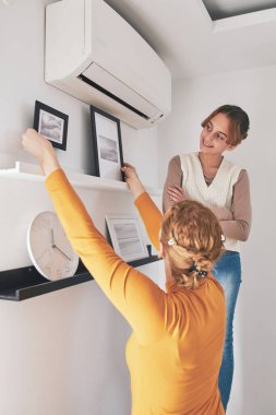 Anne ve kızı evde resim ve fotoğraf asıyorlar..