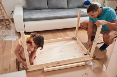 Baba ve kızı yeni bir eve taşınmak için yeni mobilya monte ediyorlar..