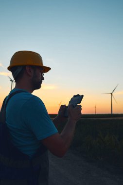 Bir yel değirmeni çiftliği parkında teftiş için İHA kullanan mühendis..