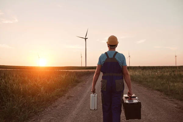 Engineer mechanic in a windmill farm park checking and servicing wind turbines.