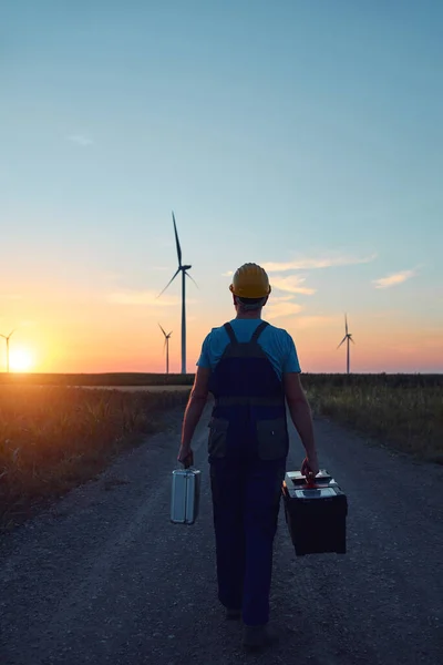 Engineer mechanic in a windmill farm park checking and servicing wind turbines.