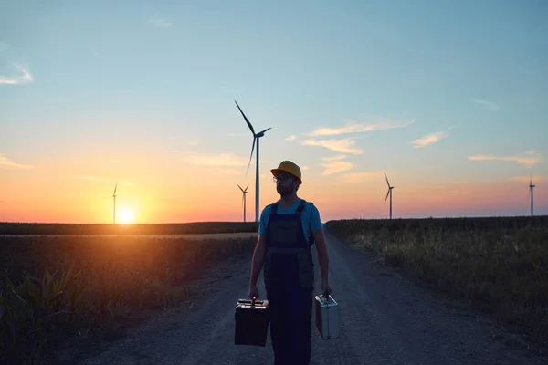 Engineer mechanic in a windmill farm park checking and servicing wind turbines.