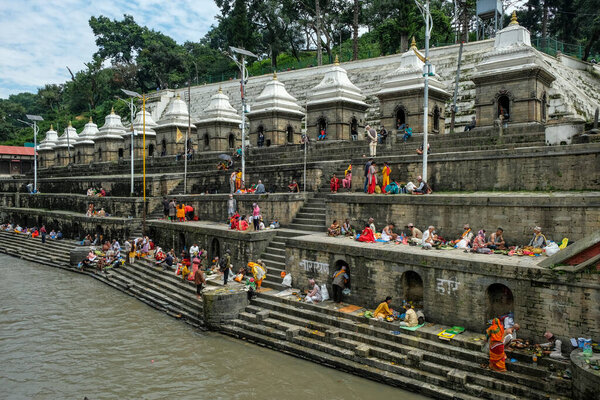 Kathmandu, Nepal - September 2021: People making offerings on the ghats of the Pashupatinath Temple on the Bagmati River on September 29, 2021 in Kathmandu, Nepal.