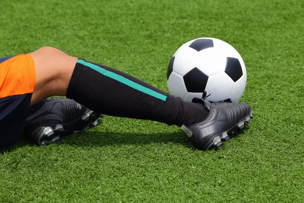 Corrediça do jogador para pegar a bola de futebol no campo de grama — Fotografia de Stock