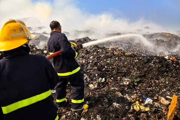 itfaiyeci yangından sonra atık yığını üzerinde su püskürtme.