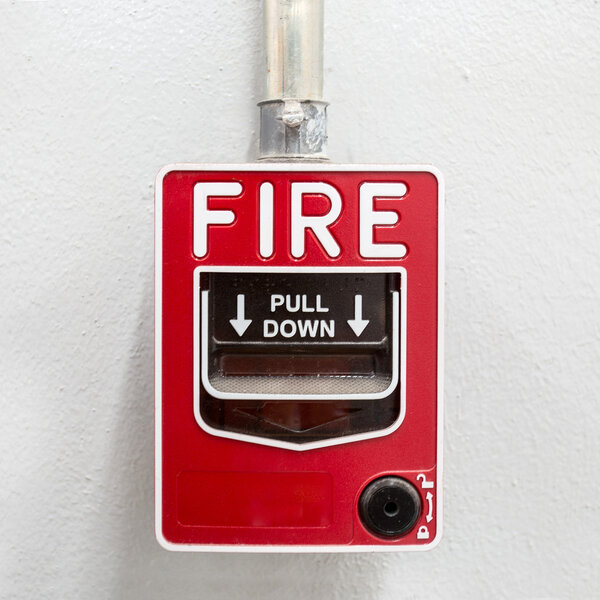 Fire alarm on white wall used to report a fire on the premises