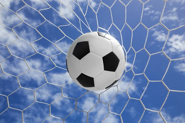 Soccer ball in goal net with blue sky — Stock Photo, Image