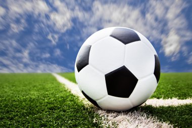 Mavi gökyüzü ile çim sahada futbol topu