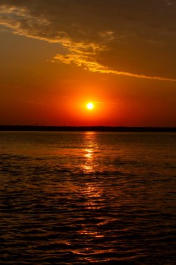 Volga Nehri 'nde şafak vakti, güneş ufuktan yükselir ve güzel bir şekilde bulutları kırmızı ışıkla aydınlatır, suda güneşli bir yol.