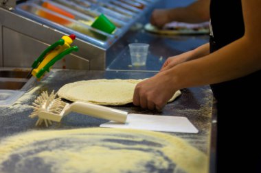 Pizza kalıplarını hamurdan çıkartıyor ve restoranın yakın planında pizza elleri var.