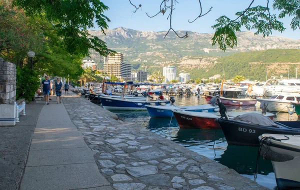 Montenegro - Budva: 9 de septiembre de 2021: Marina con muchos yates de vela, barcos y personas a pie con vista a la montaña de fondo. Vista de la ciudad turística de Budva con su puerto y turistas — Foto de Stock