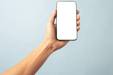 Mavi arkaplanda kırpma yolu ile izole edilmiş boş ekran ile cep telefonu tutan el işi adamı