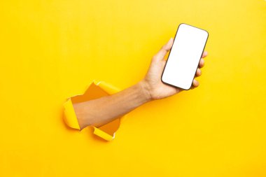 man hand holding a blank screen smart phone on a yellow backgroun