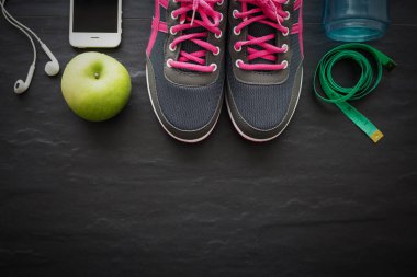 Fitness sağlıklı konsept, spor ayakkabı, elma, su ve siyah arka plan üzerinde akıllı telefon, üst görünüm