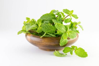 Beyaz arka planda izole edilmiş ahşap bir kasedeki nane yaprağı. 