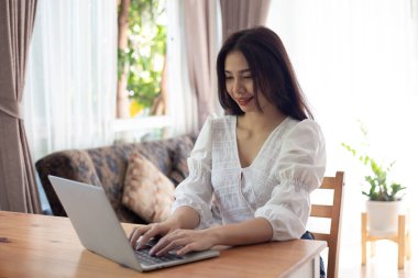 Genç Asyalı kadın dizüstü bilgisayar kullanıyor. İş kadını evden çalışıyor.