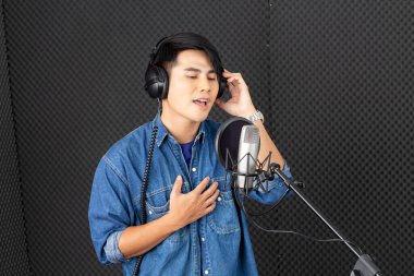 Asian male singer recording in the studio.