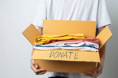 Donation Concept, man holding clothes with donate box in white background room.