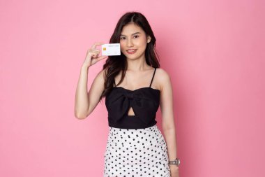 Cheerful smiling Asian woman holding card isolated on pink background.