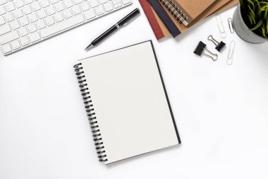 Üst manzara, boş defter ve ofis malzemeleri masanın üstünde..
