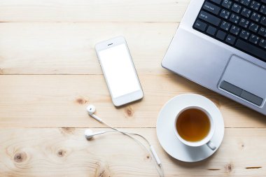akıllı telefon çay fincanı ve bilgisayar ahşap masa manzaralı.