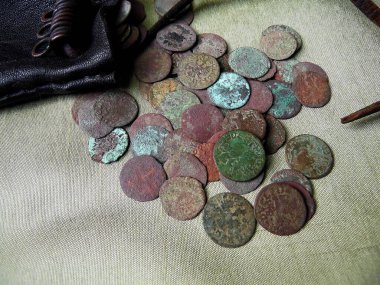 17. yüzyılın antika bakır paraları, parlak bir arka planda deri bir cüzdana saçılmış, yakın plan, çeyrek peni.