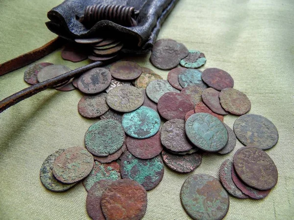 antique copper coins of the 17th century, scattered from a leather wallet on a light background, close-up, a quarter of a penny