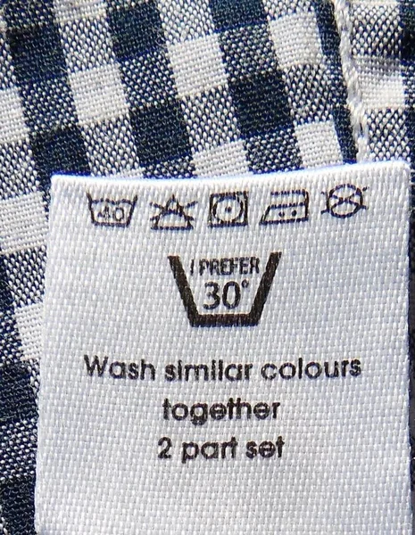Care instructions and fabric composition clothing label closeup on textile background
