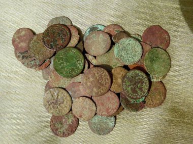Copper coins of Europe of the 17th century on a green cloth, close-up