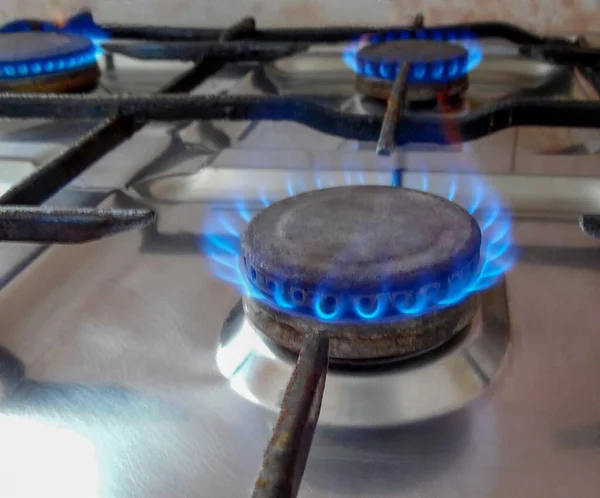 Gas stove at home, propane natural gas burns in the kitchen, blue flames of burners for cooking. The concept of the economy of Ukraine and Europe, the cost of gas, heat, EU sanctions, crisis, embargo