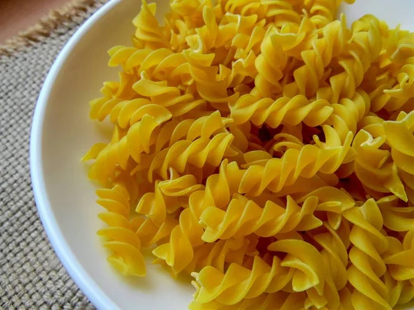 twisted pasta on a light dish against the background of coarse cloth