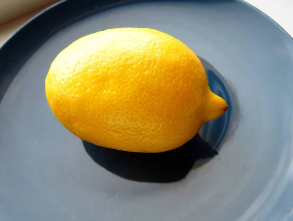青い皿の上に熟したレモンが一つ — ストック写真