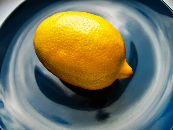 one ripe lemon on a blue dish, close-up