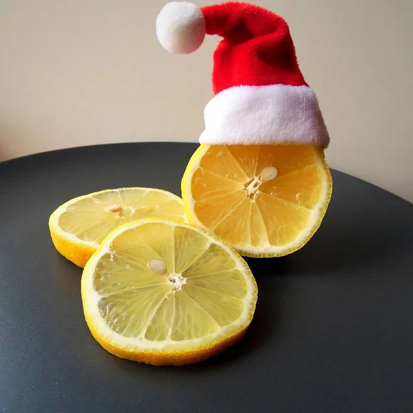 santa's hat and lemon cut into slices on a gray plate and light background, christmas theme