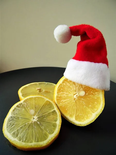 santa\'s hat and lemon cut into slices on a gray plate and light background, christmas theme