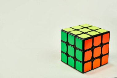 Beyaz zemin üzerinde sarı, yeşil ve turuncu renkli Rubik küpünü çözdük..