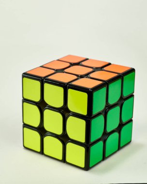 Beyaz arka planda sarı, yeşil ve turuncu renkli Rubik küpünü çözdük..