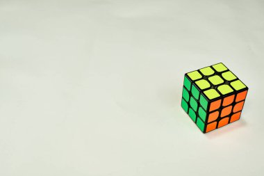 Sarı, yeşil ve turuncu renkli Rubik küpünü beyaz arkaplanda kopyalama alanı ile çözdüm. .