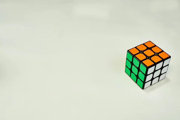 Beyaz, yeşil ve turuncu renkli Rubik küpünü beyaz arkaplanda kopyalama alanı ile çözdük.