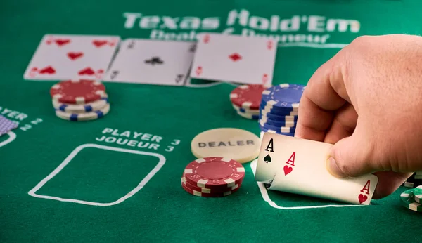 Hands of a man showing a pair of aces and poker chips — Stock Photo, Image