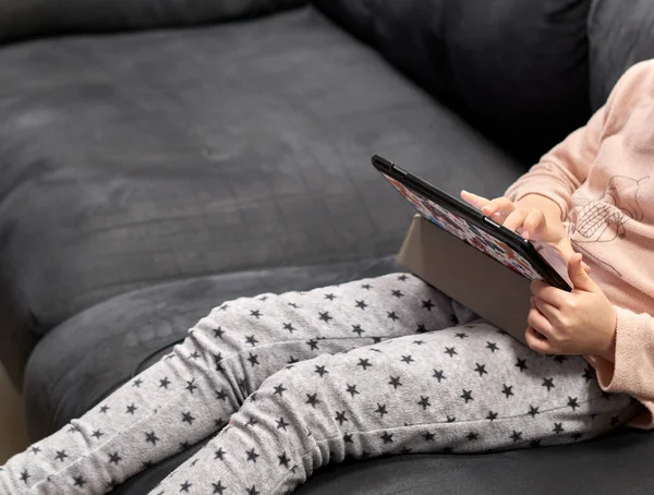 Tanınmayan bir kız kanepede tablet kullanıyor.
