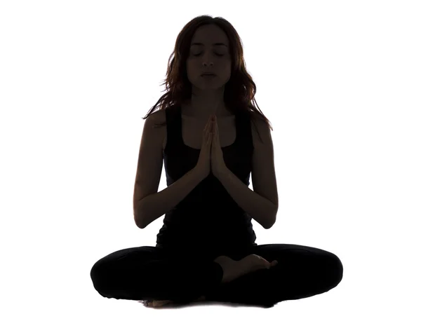 Silhouette of a young woman sitting and meditating — Stock Photo, Image