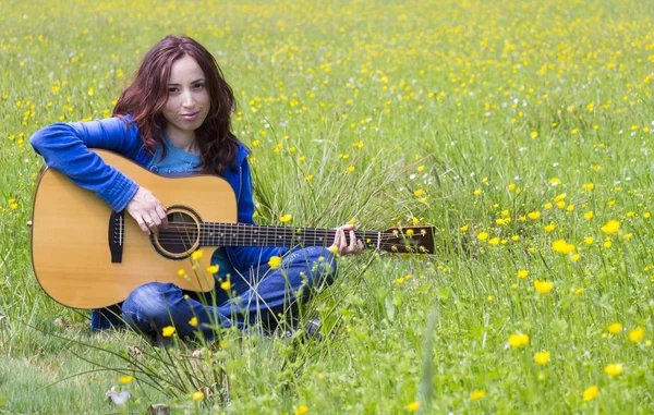 Young woman playing an acoutic guitar in the fields — Stock Photo, Image